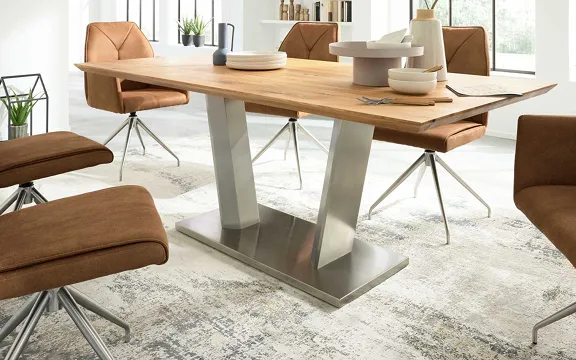 Moderner Esstisch mit Holzplatte und Metallgestell, umgeben von braunen Polsterstühlen im hellen Raum.