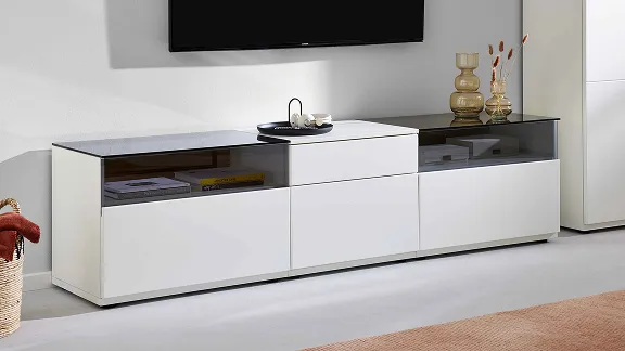 Detailansicht eines weißen Interliving TV-Lowboards mit dunklen Glasabdeckplatten und Stauraum.